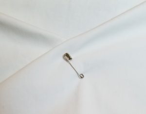 safety pin pinned to hold two folded pieces of fabric together