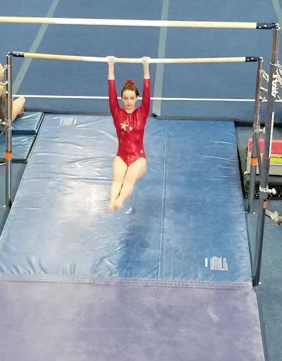 Tayler swinging on the lower bar of the uneven bars in Grand Junction